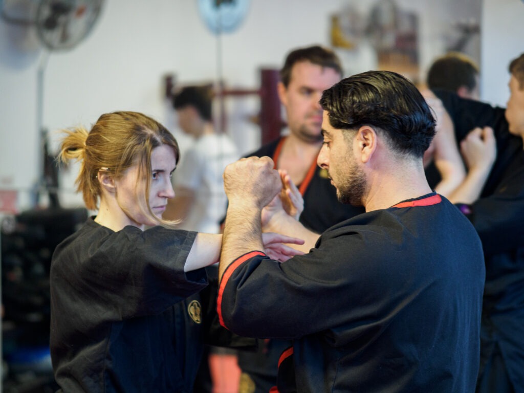 Zwei Schüler der WingChun Gruppe in Heidelberg, eine Frau und ein Mann, trainieren miteinander das kampfkunstpezifische Programm um die Fähigkeiten zu verbessern. Die Fitness verbessert sich durch diese Übungen positiv.